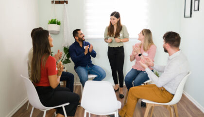 Congratulations on your progress! AA support group clapping to a female member for her positive improvement on her mental health and alcohol addiction